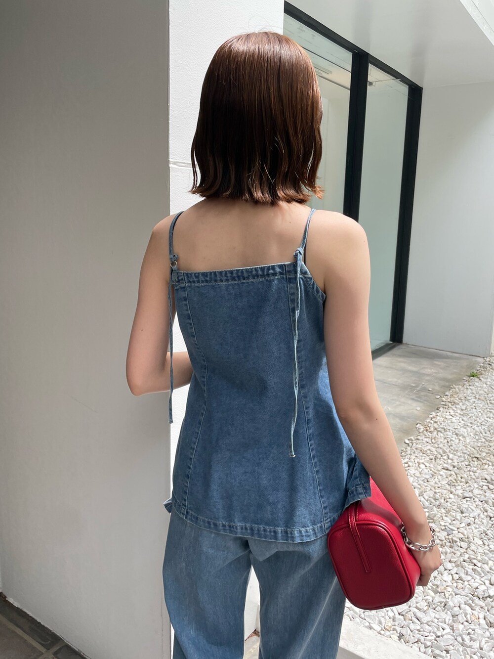 レッド系のハンドバッグ、ホワイト系のサンダル、ブルー系のキャミソールを着用したレディースの春コーディネートの4枚目の写真