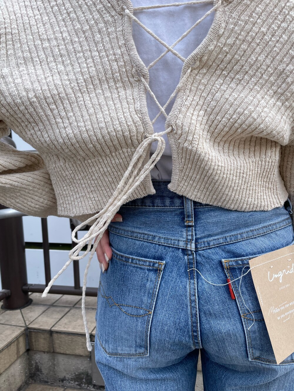 ホワイト系のハンドバッグ、ホワイト系のTシャツ/カットソー、ブルー系のデニムパンツを着用したレディースの冬コーディネートの5枚目の写真