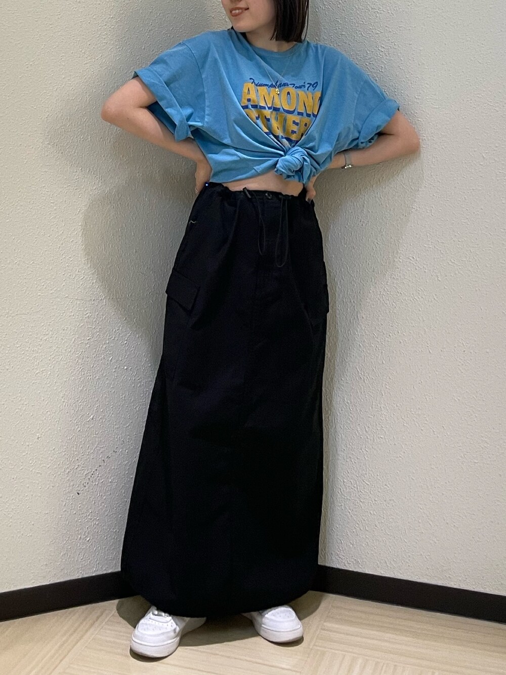 ブルー系のTシャツ/カットソー、ブラック系のスカート、ゴールド系のネックレスを着用したレディースの春コーディネートの4枚目の写真