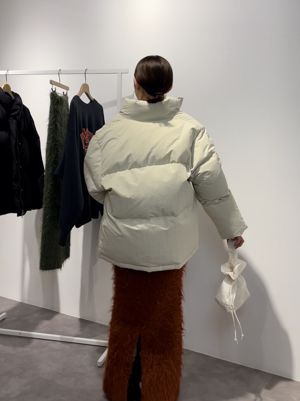 ブラック系のブーツ、ホワイト系のダウンジャケット/コート、オレンジ系のスカートを着用したレディースの秋コーディネートの6枚目の写真