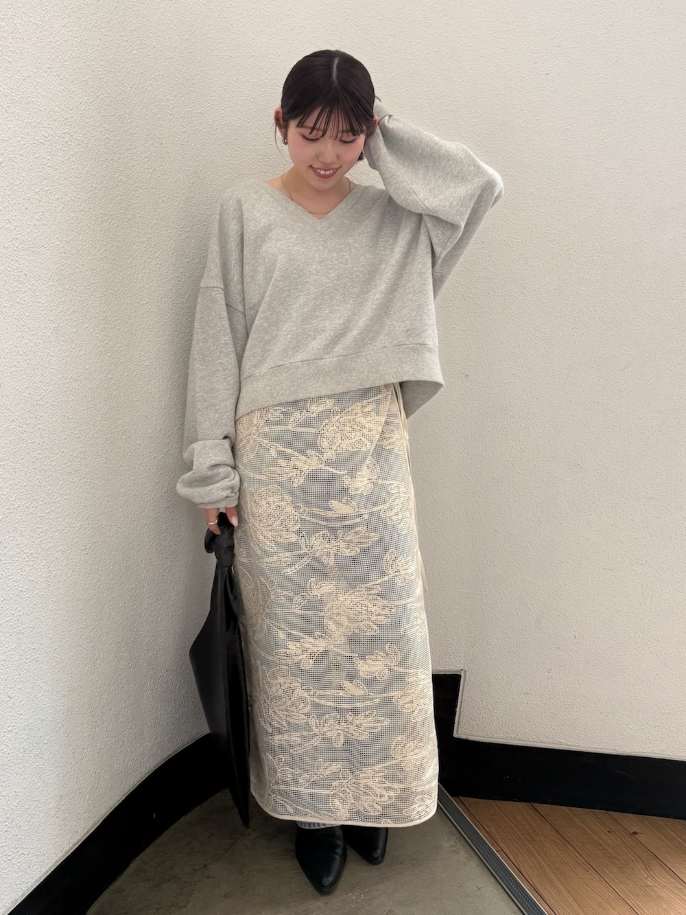 ブラック系のハンドバッグ、ブラック系のブーツ、ブルー系のデニムパンツを着用したレディースの春コーディネートの2枚目の写真