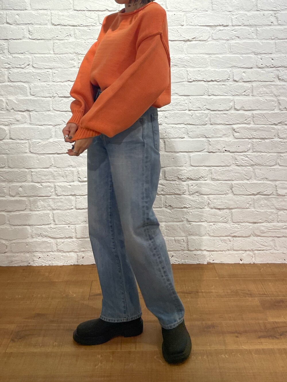 オレンジ系のニット/セーター、ブルー系のデニムパンツ、ブラック系のブーツを着用したレディースの冬コーディネートの7枚目の写真