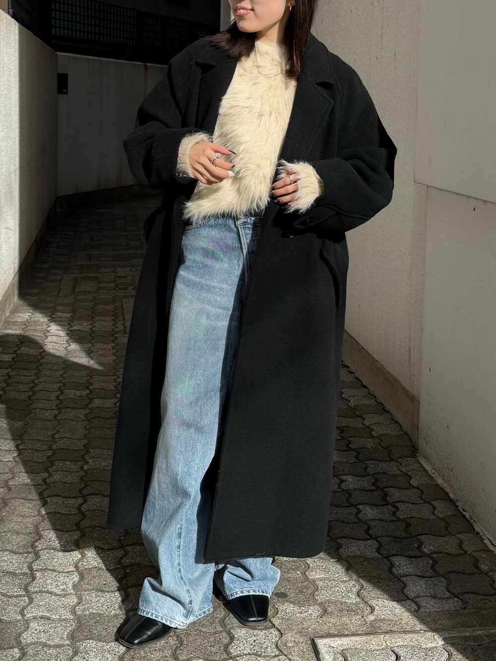 ブルー系のデニムパンツ、ブラック系のブーツ、ブラック系のチェスターコートを着用したレディースの冬コーディネートの6枚目の写真