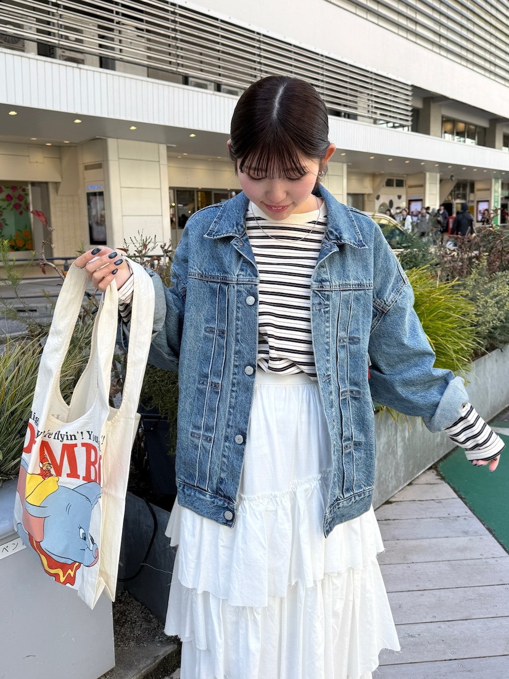 ホワイト系のスカート、ベージュ系のハンドバッグ、ブルー系のデニムジャケットを着用したレディースの冬コーディネートの4枚目の写真