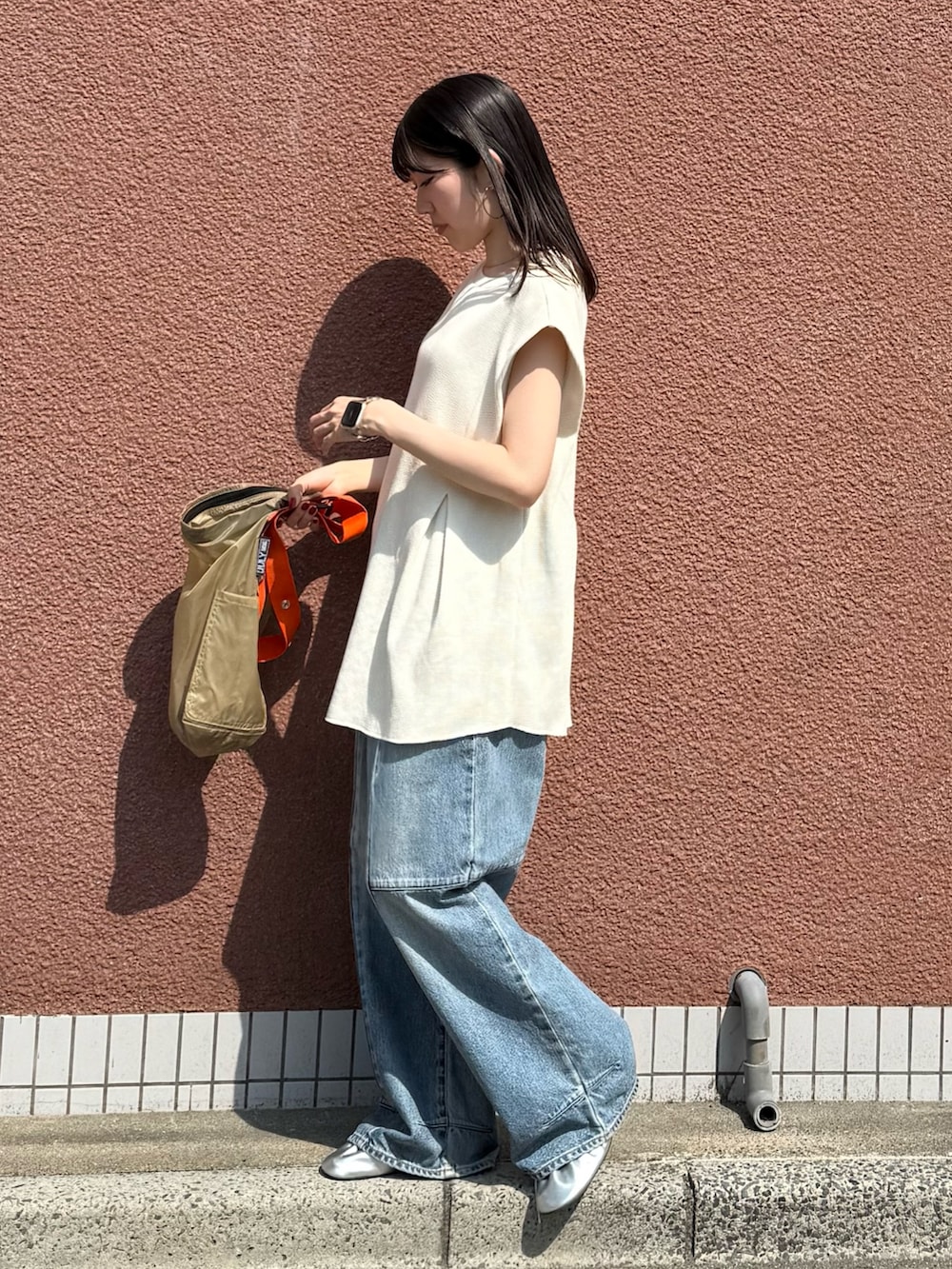 ホワイト系のタンクトップ、ブルー系のデニムパンツ、ベージュ系のショルダーバッグを着用したレディースの夏コーディネートの2枚目の写真