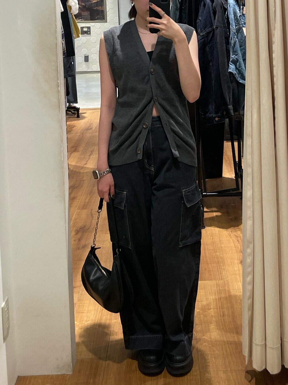 グレー系のベスト、ブラック系のブーツ、ブラック系のデニムパンツを着用したレディースの秋コーディネートの2枚目の写真