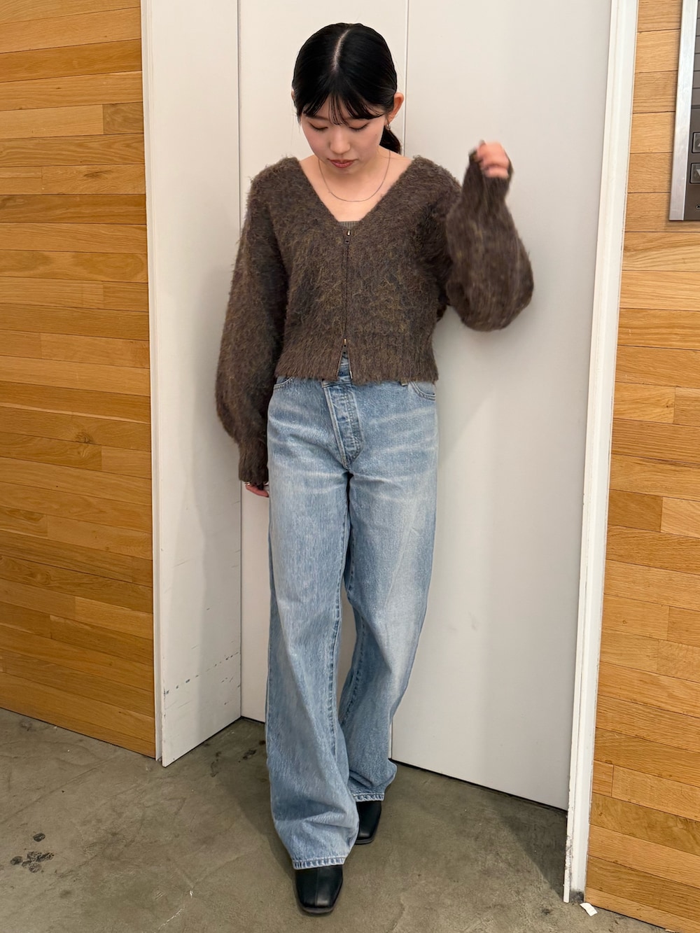 ブルー系のデニムパンツ、ブラック系のブーツ、ブラウン系のカーディガン/ボレロを着用したレディースの冬コーディネートの2枚目の写真