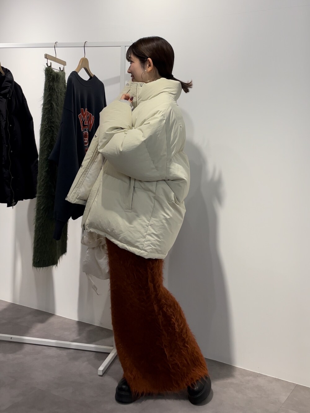 ブラック系のブーツ、ホワイト系のダウンジャケット/コート、オレンジ系のスカートを着用したレディースの秋コーディネートの2枚目の写真