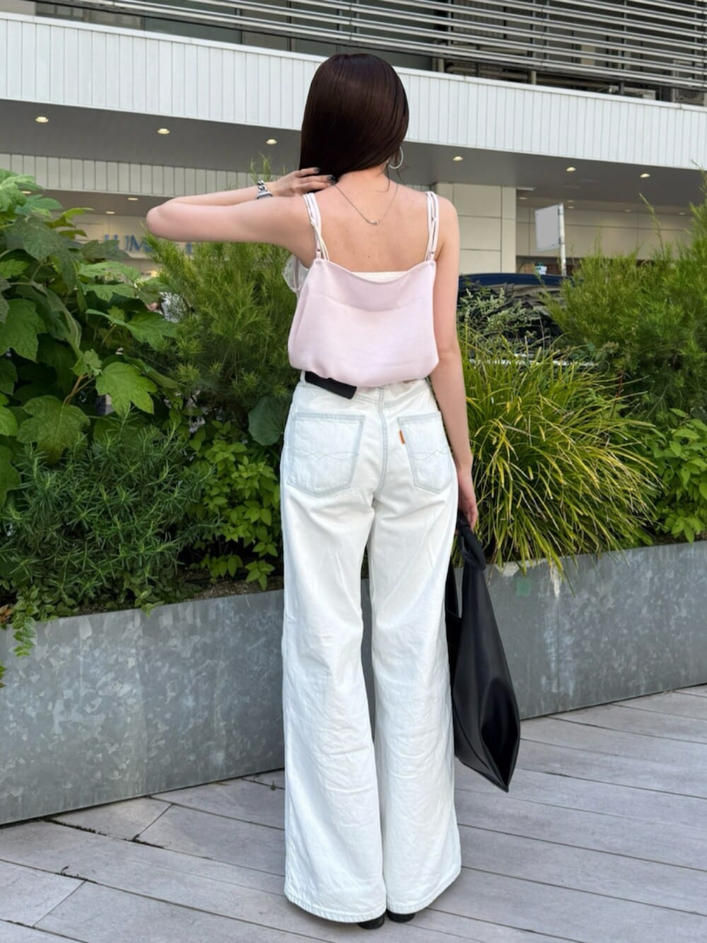 ブラック系のハンドバッグ、ホワイト系のデニムパンツ、ピンク系のキャミソールを着用したレディースの春コーディネートの3枚目の写真