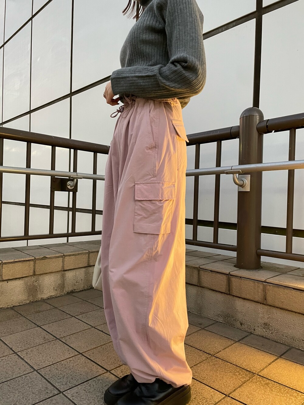 ピンク系のカーゴパンツ、ホワイト系のハンドバッグ、グレー系のニット/セーターを着用したレディースの冬コーディネートの2枚目の写真