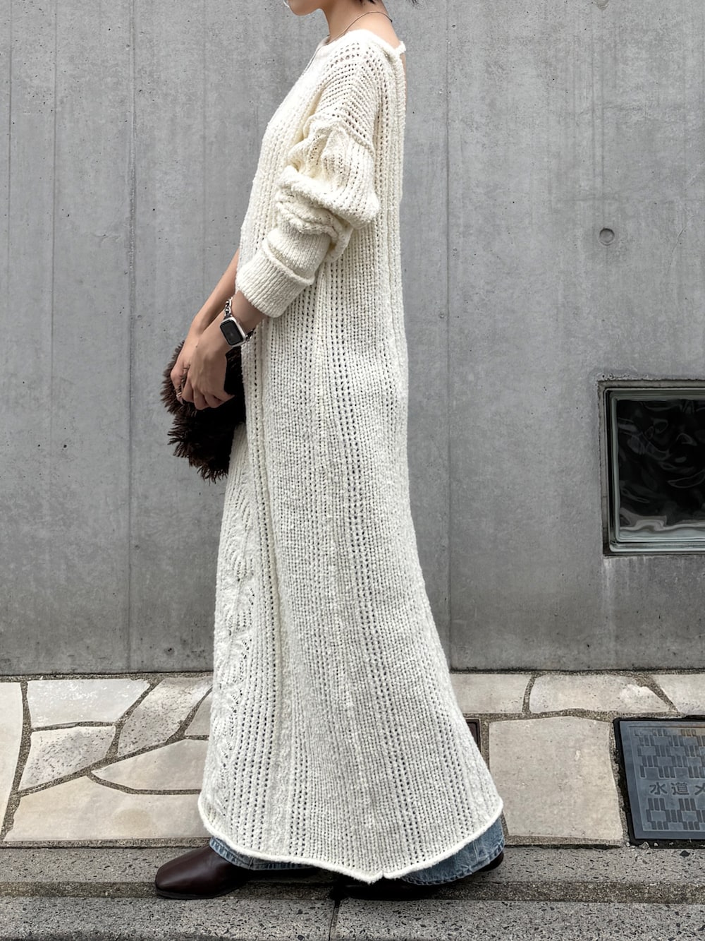 ホワイト系のワンピース、ブルー系のデニムパンツ、ブラウン系のブーツを着用したレディースの冬コーディネートの4枚目の写真