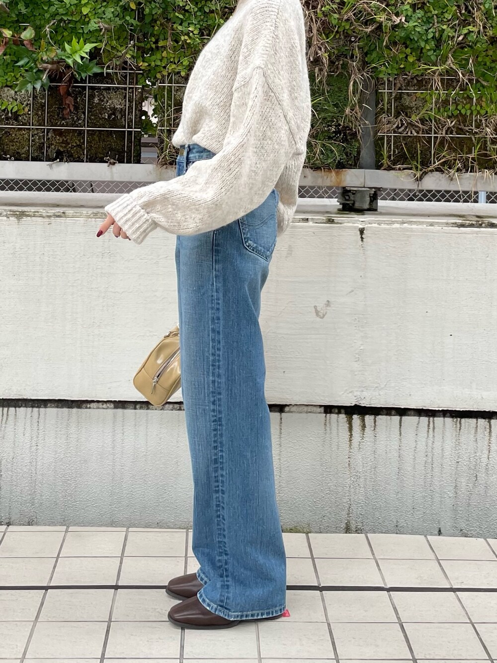 ブルー系のデニムパンツ、ブラウン系のブーツ、ホワイト系のニット/セーターを着用したレディースの秋コーディネートの6枚目の写真