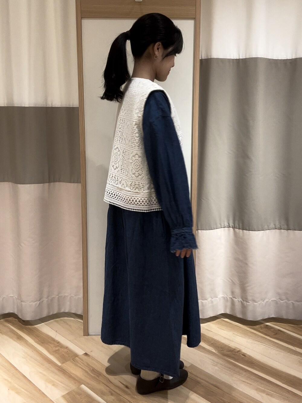 ブルー系のワンピース、ブラウン系のドレスシューズ、ホワイト系のベストを着用したレディースの夏コーディネートの2枚目の写真