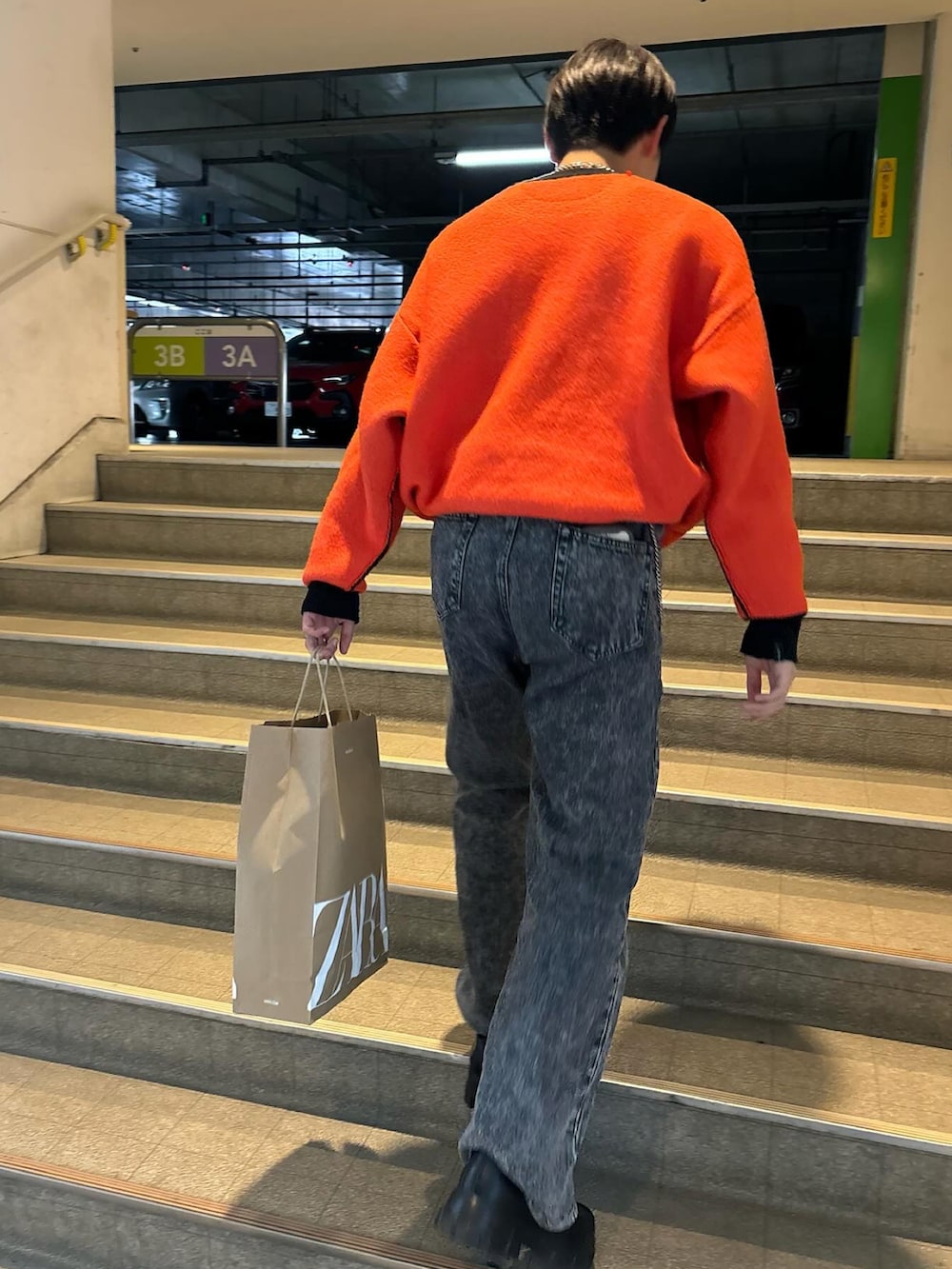 オレンジ系のニット/セーター、ブラック系のローファー、ブラック系のデニムパンツを着用したメンズの春コーディネートの2枚目の写真