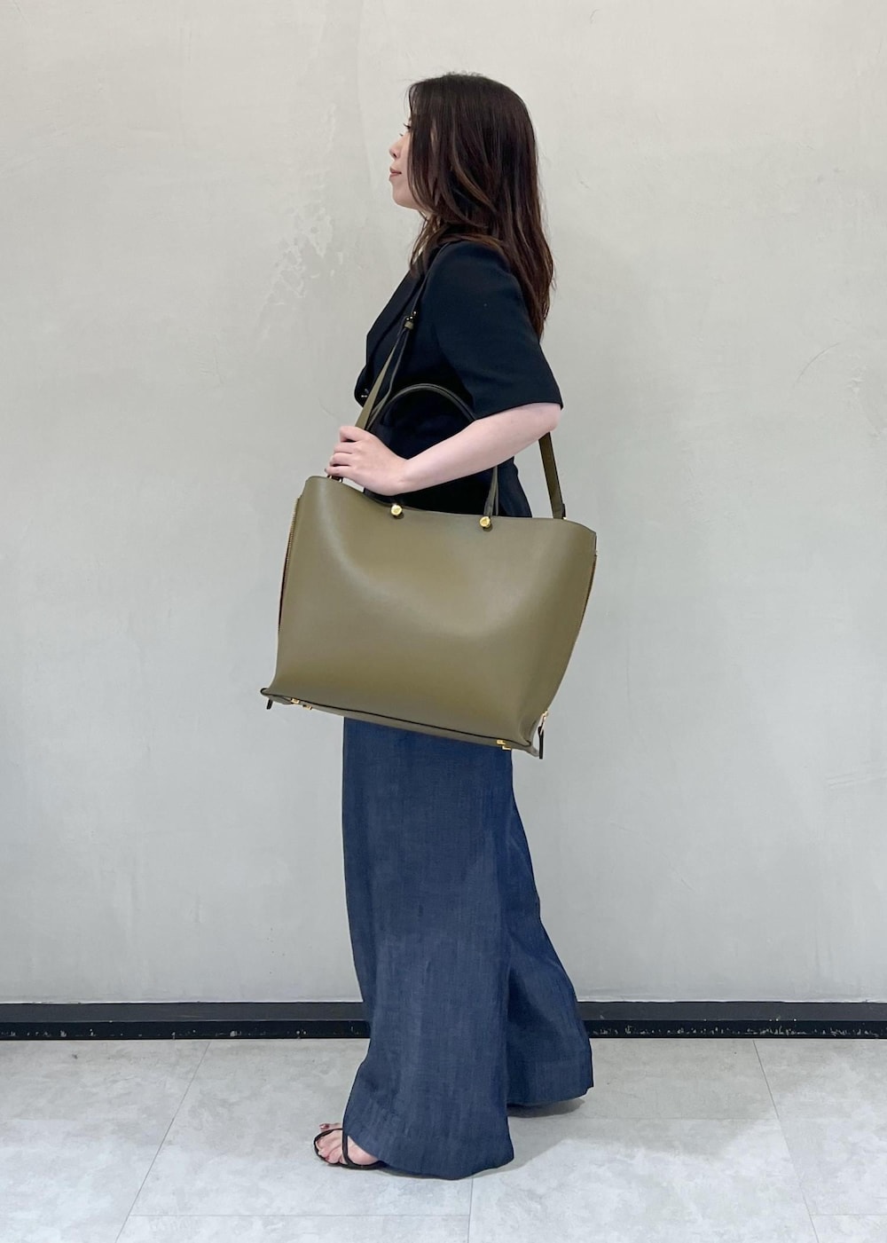 グリーン系のトートバッグ、ブラック系のテーラードジャケット、ブルー系のその他パンツを着用したレディースの夏コーディネートの3枚目の写真