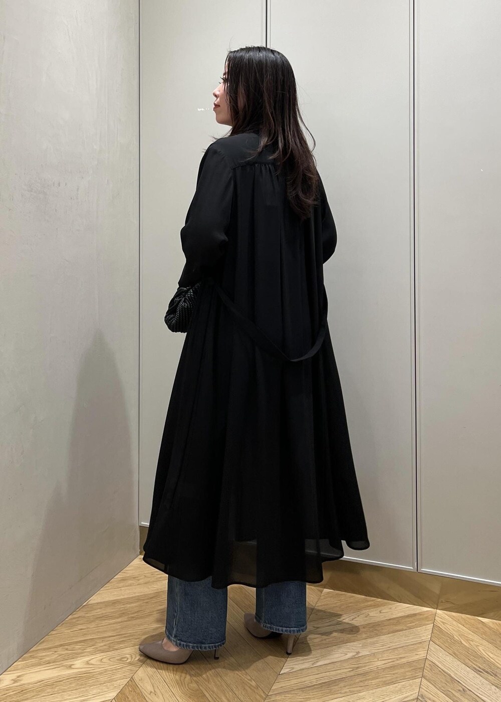 ブルー系のデニムパンツ、ブラック系のクラッチバッグを着用したレディースの春コーディネートの3枚目の写真