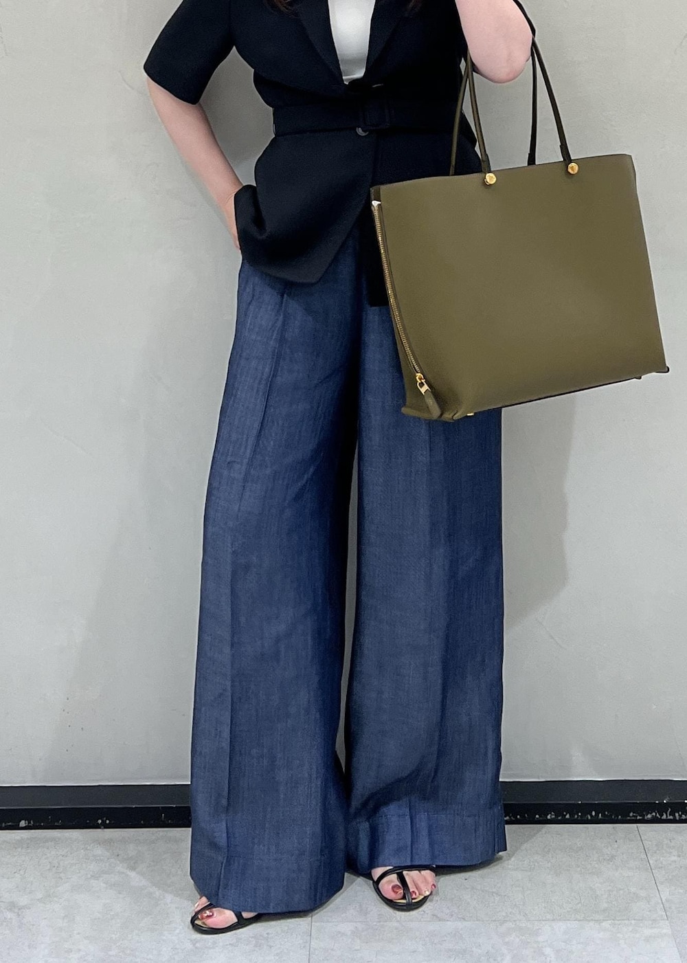 グリーン系のトートバッグ、ブラック系のテーラードジャケット、ブルー系のその他パンツを着用したレディースの夏コーディネートの6枚目の写真