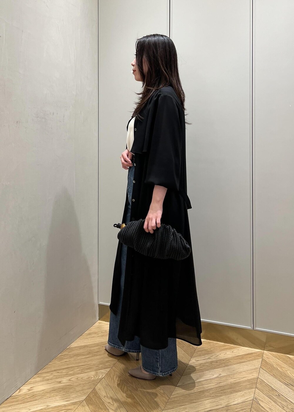 ブルー系のデニムパンツ、ブラック系のクラッチバッグを着用したレディースの春コーディネートの2枚目の写真