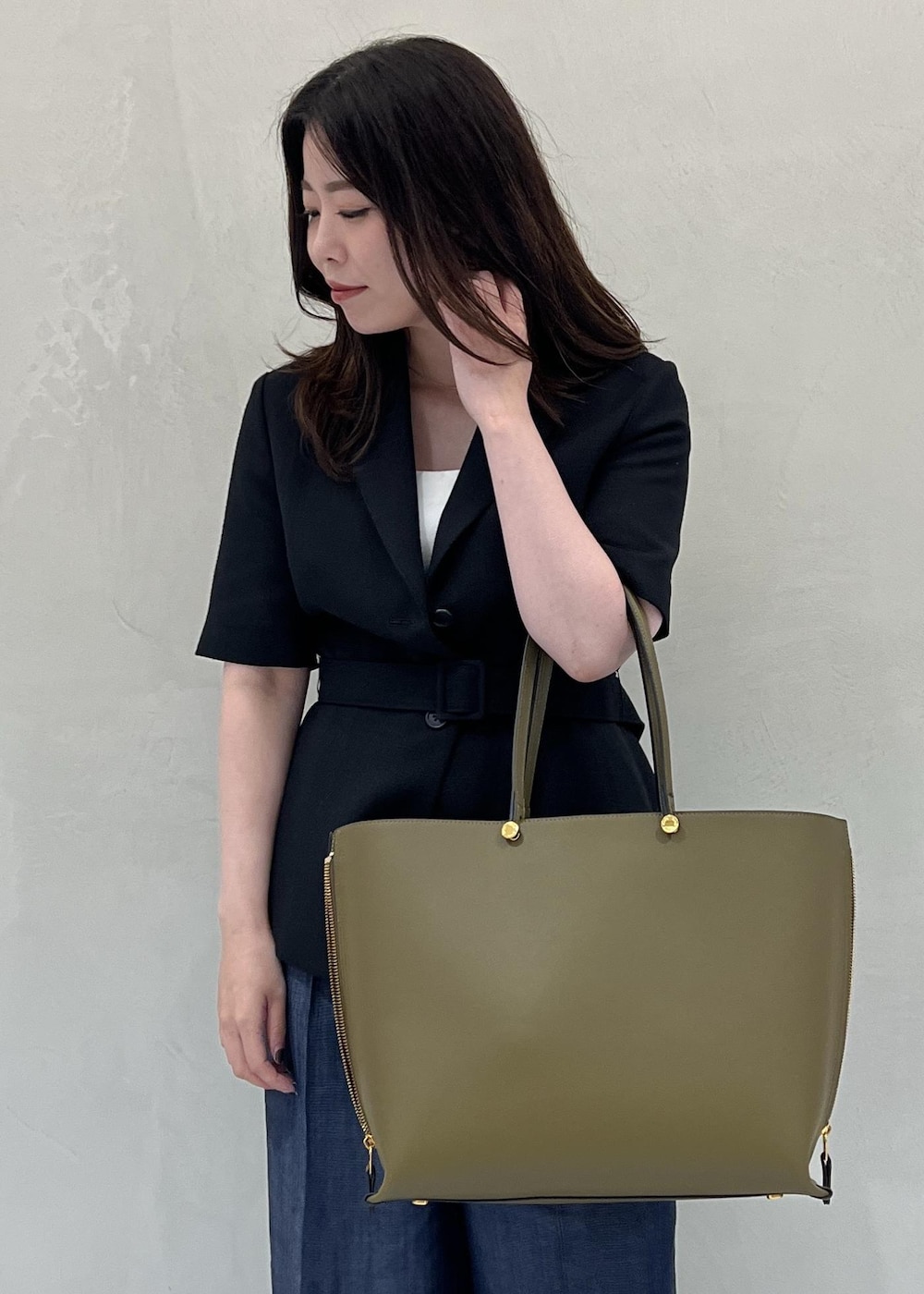 グリーン系のトートバッグ、ブラック系のテーラードジャケット、ブルー系のその他パンツを着用したレディースの夏コーディネートの5枚目の写真