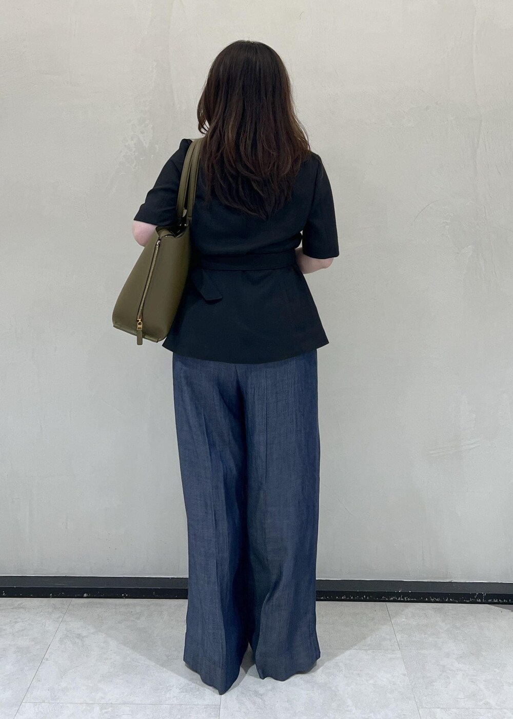 グリーン系のトートバッグ、ブラック系のテーラードジャケット、ブルー系のその他パンツを着用したレディースの夏コーディネートの4枚目の写真