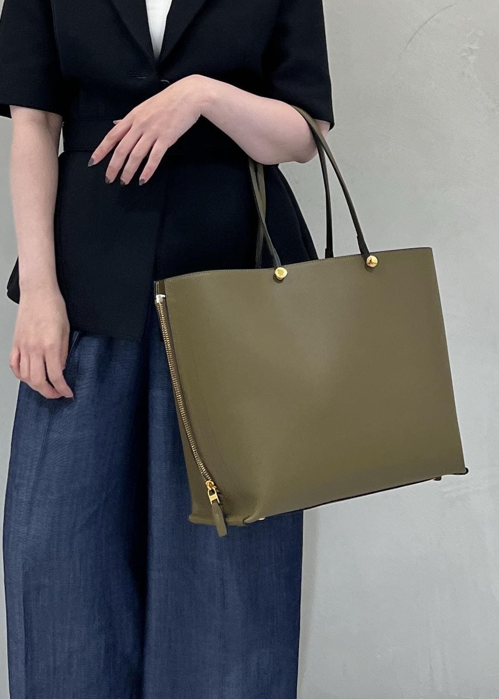 グリーン系のトートバッグ、ブラック系のテーラードジャケット、ブルー系のその他パンツを着用したレディースの夏コーディネートの7枚目の写真