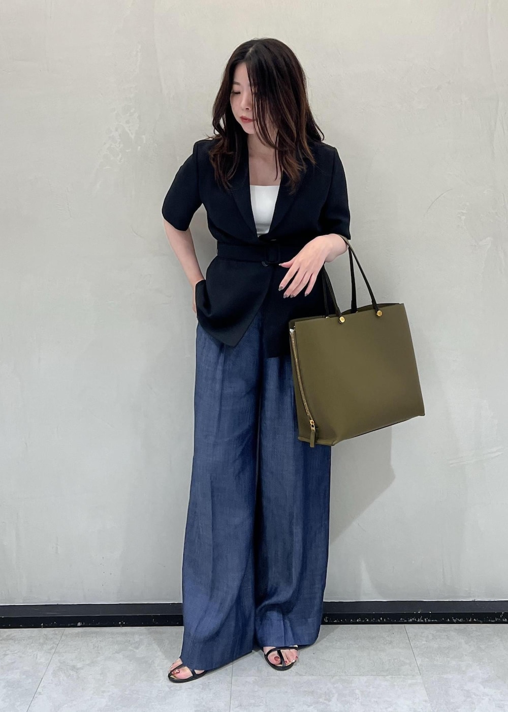 グリーン系のトートバッグ、ブラック系のテーラードジャケット、ブルー系のその他パンツを着用したレディースの夏コーディネートの2枚目の写真