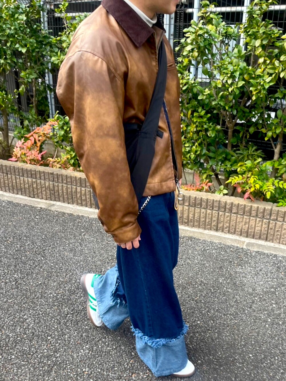 ブラウン系のライダースジャケット、ブルー系のデニムパンツ、イエロー系のキーケース/キーアクセサリーを着用したメンズの冬コーディネートの2枚目の写真