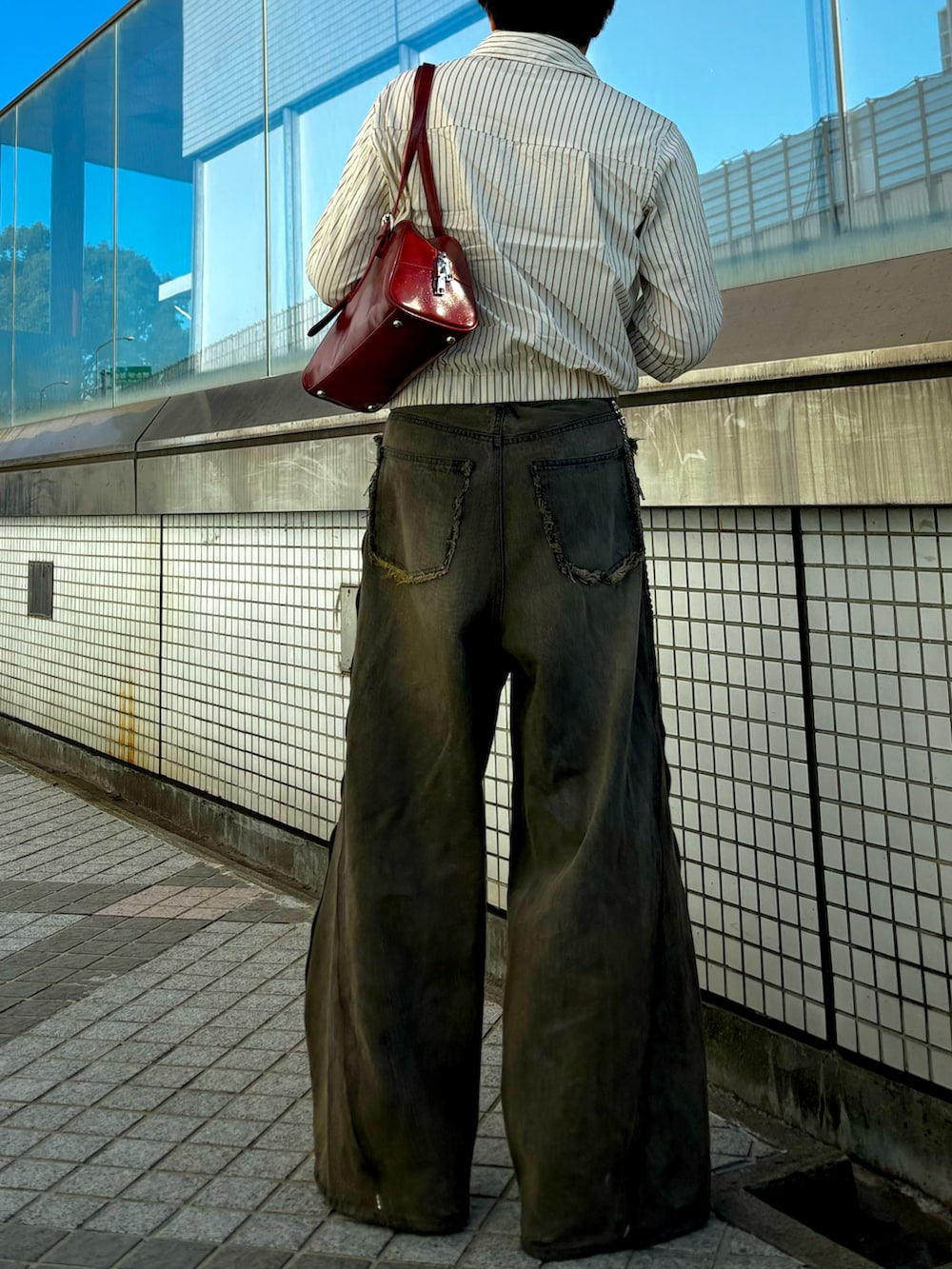 ベージュ系のブルゾン、ブラウン系のデニムパンツ、レッド系のブーツを着用したメンズの秋コーディネートの3枚目の写真