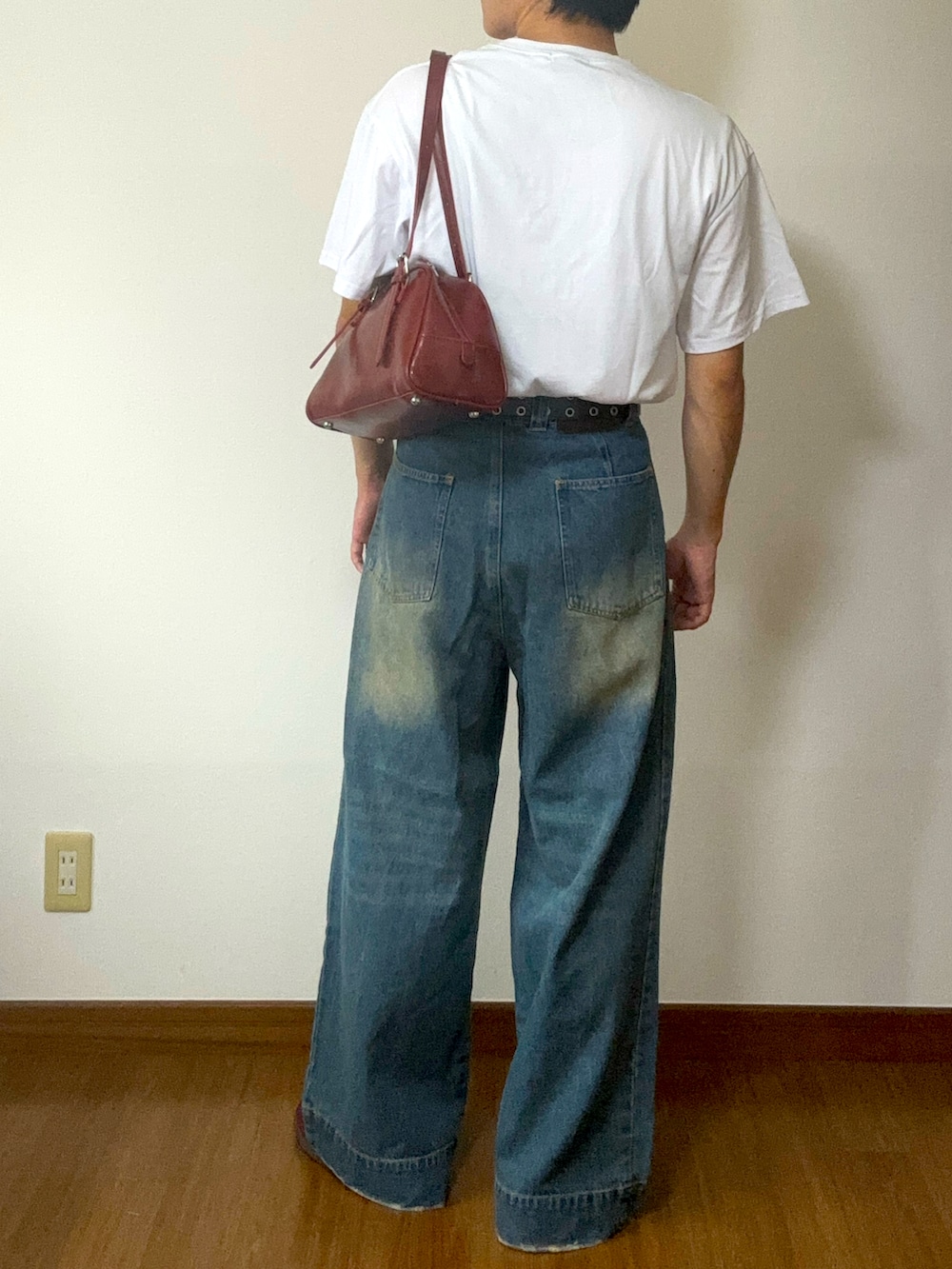 オレンジ系のTシャツ/カットソー、ブルー系のデニムパンツ、レッド系のスニーカーを着用したメンズの秋コーディネートの3枚目の写真