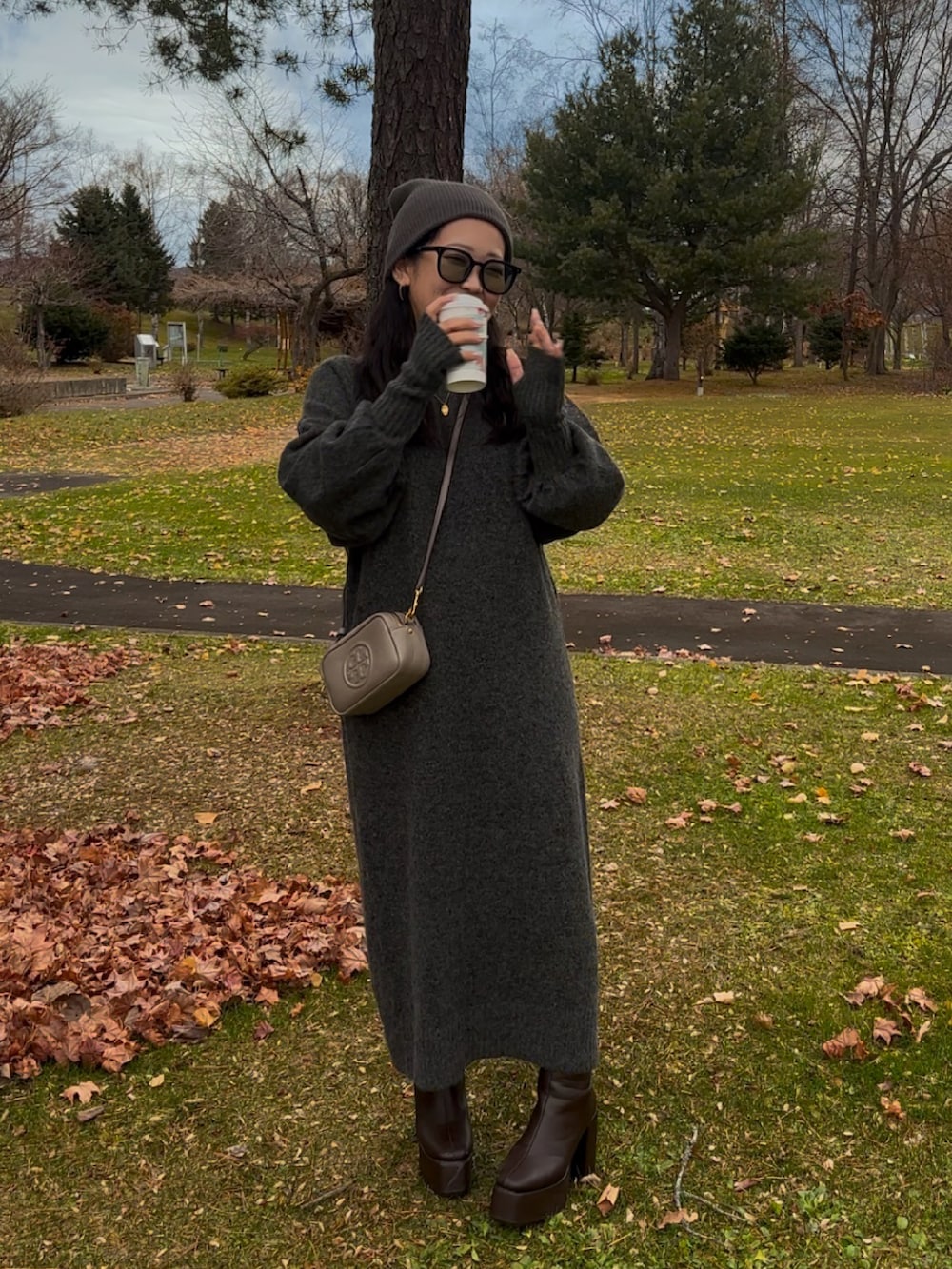 グレー系のワンピース、グレー系のショルダーバッグ、ブラウン系のブーツを着用したレディースの秋コーディネートの4枚目の写真