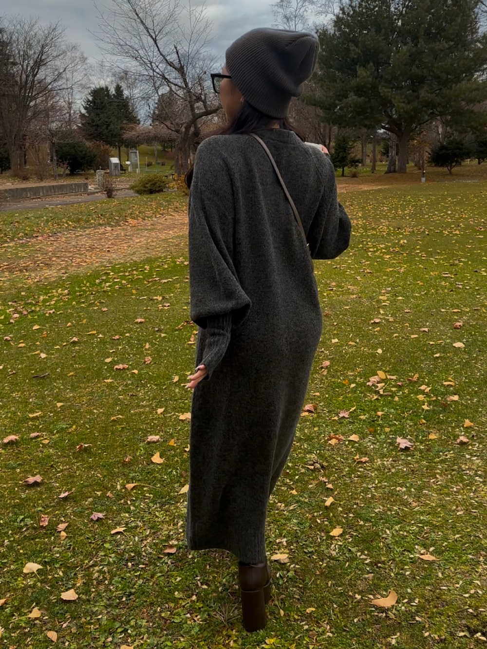 グレー系のワンピース、グレー系のショルダーバッグ、ブラウン系のブーツを着用したレディースの秋コーディネートの3枚目の写真