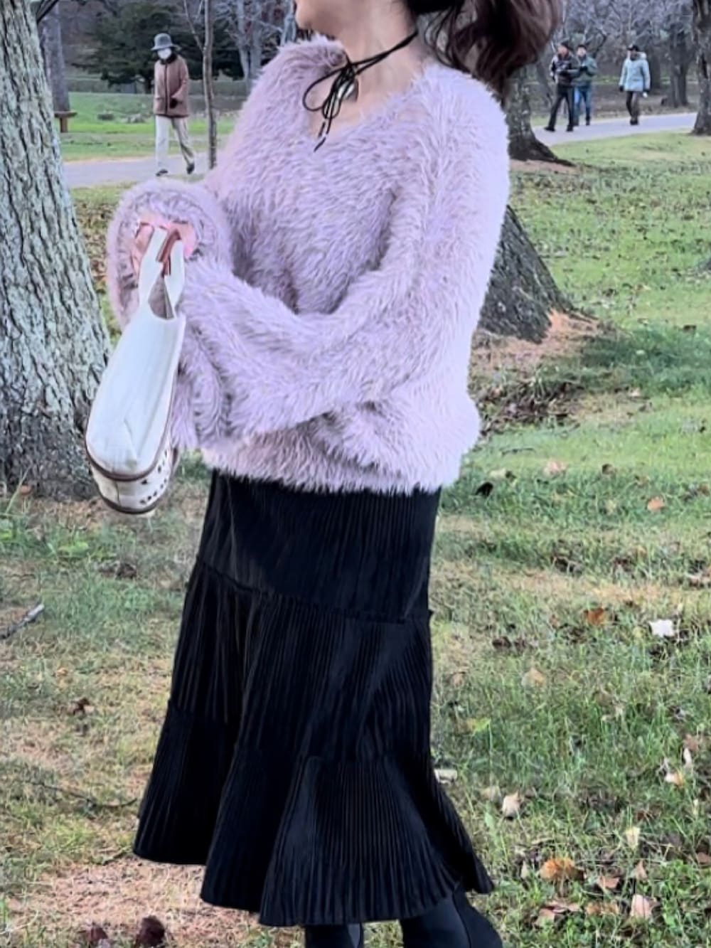 ブラウン系のブルゾン、ピンク系のニット/セーター、ベージュ系のハンドバッグを着用したレディースの冬コーディネートの2枚目の写真