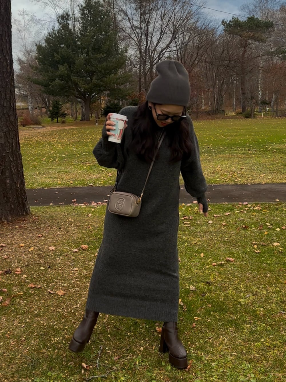 グレー系のワンピース、グレー系のショルダーバッグ、ブラウン系のブーツを着用したレディースの秋コーディネートの2枚目の写真