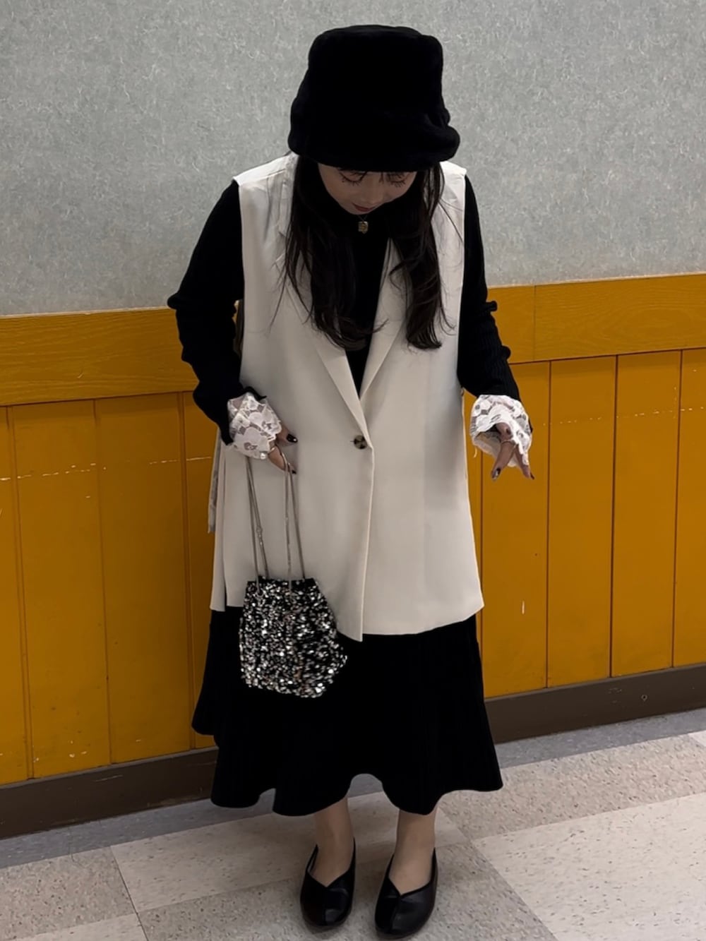 ブラック系のパンプス、ブラック系のニット/セーター、ホワイト系のベストを着用したレディースの秋コーディネートの2枚目の写真