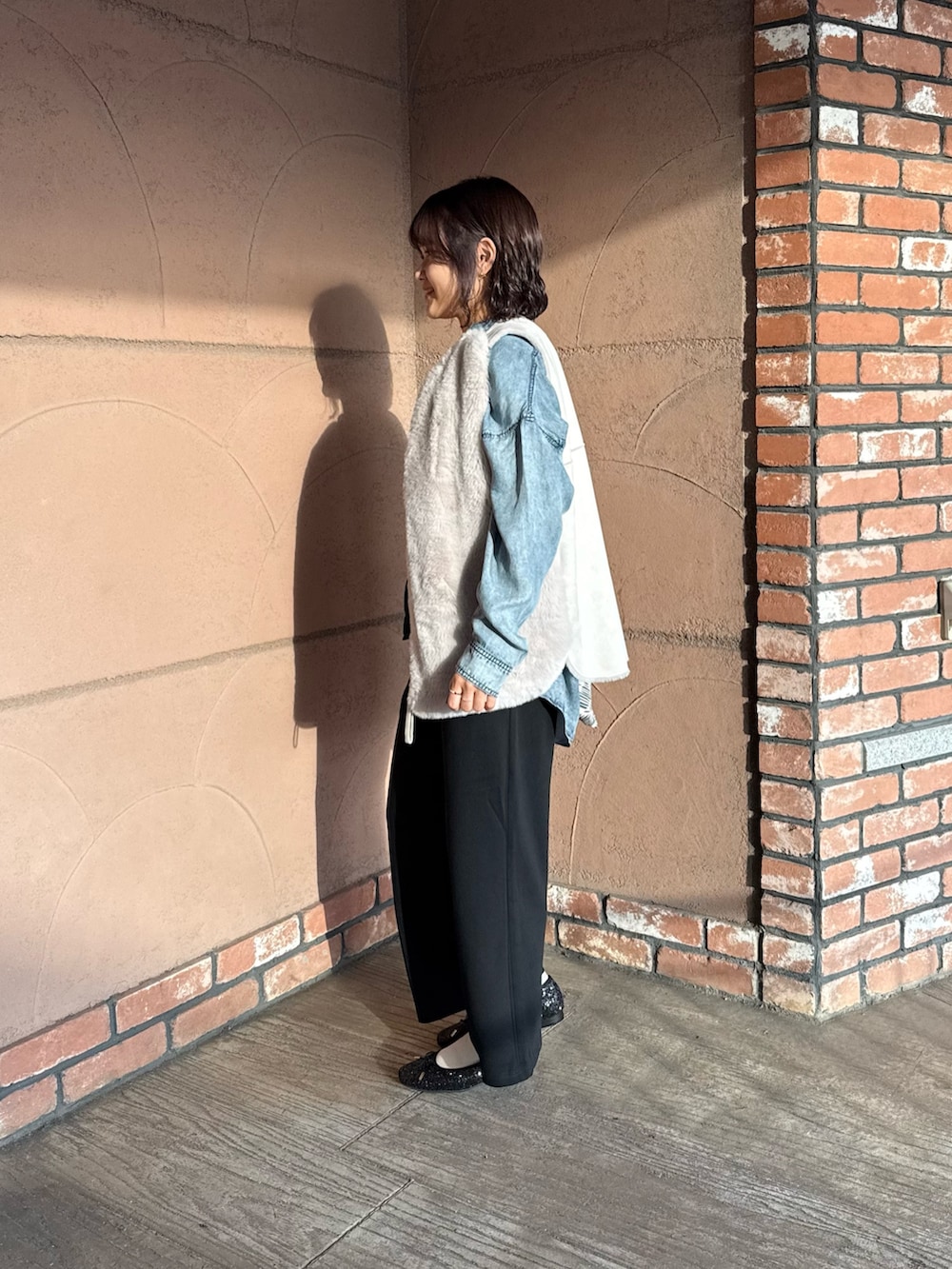 ブラック系のスウェットパンツ、ブラック系のバレエシューズ、グレー系のベストを着用したレディースの秋コーディネートの3枚目の写真