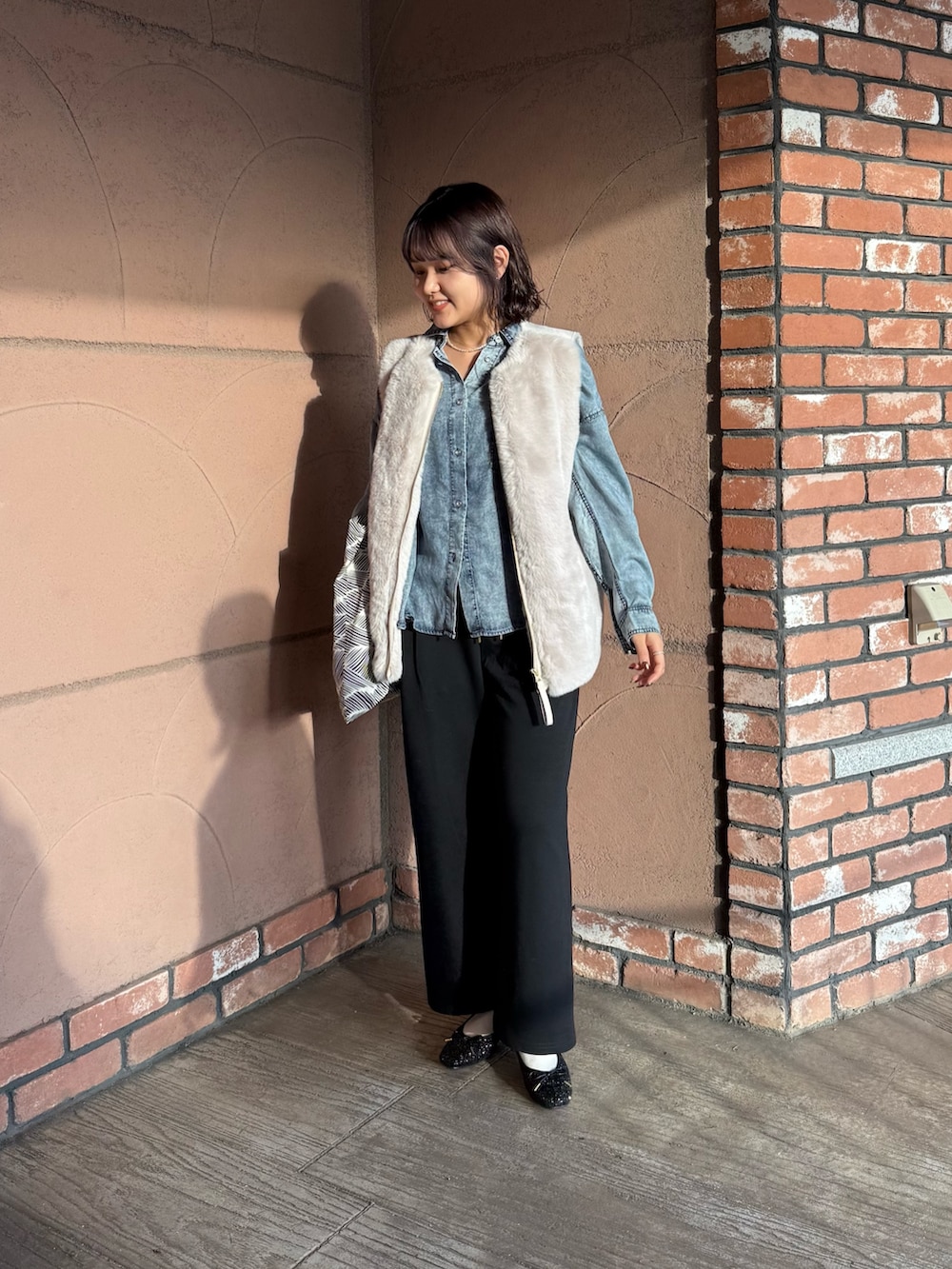 ブラック系のスウェットパンツ、ブラック系のバレエシューズ、グレー系のベストを着用したレディースの秋コーディネートの2枚目の写真