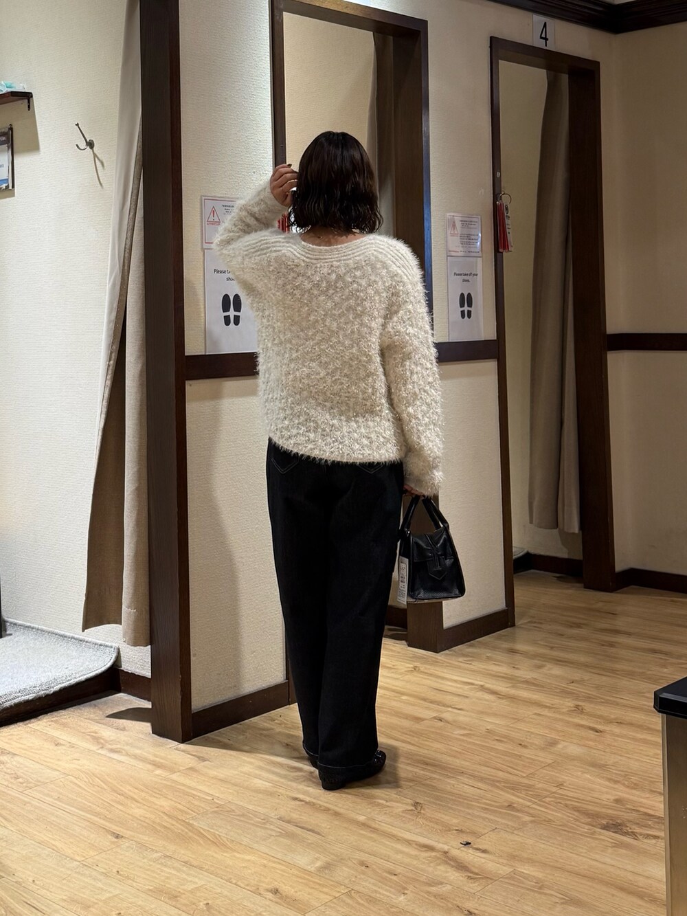 ホワイト系のニット/セーター、ブラック系のデニムパンツ、ブラック系のボストンバッグを着用したレディースの秋コーディネートの3枚目の写真