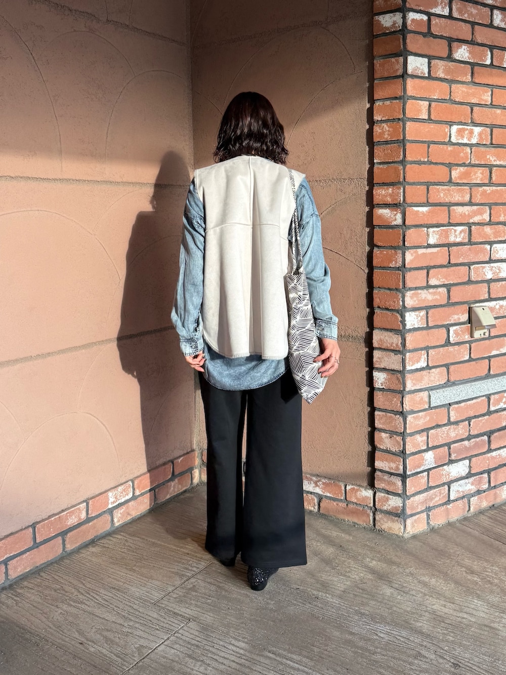 ブラック系のスウェットパンツ、ブラック系のバレエシューズ、グレー系のベストを着用したレディースの秋コーディネートの4枚目の写真