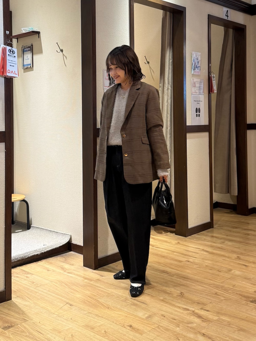 ベージュ系のニット/セーター、ブラック系のボストンバッグ、ブルー系のデニムパンツを着用したレディースの秋コーディネートの2枚目の写真