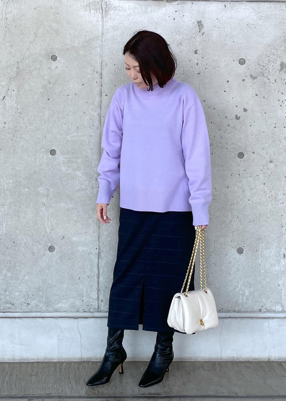 ブラック系のブーツ、ホワイト系のハンドバッグ、ブルー系のスカートを着用したレディースの秋コーディネートの3枚目の写真