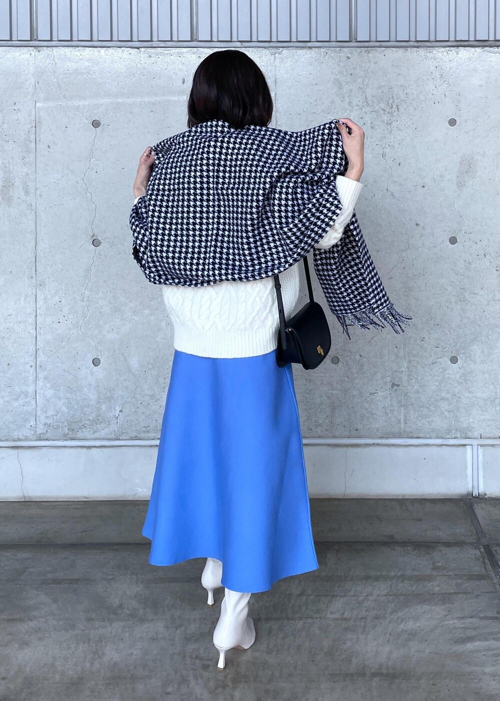 ブラック系のショルダーバッグ、ホワイト系のブーツ、ブルー系のスカートを着用したレディースの秋コーディネートの5枚目の写真