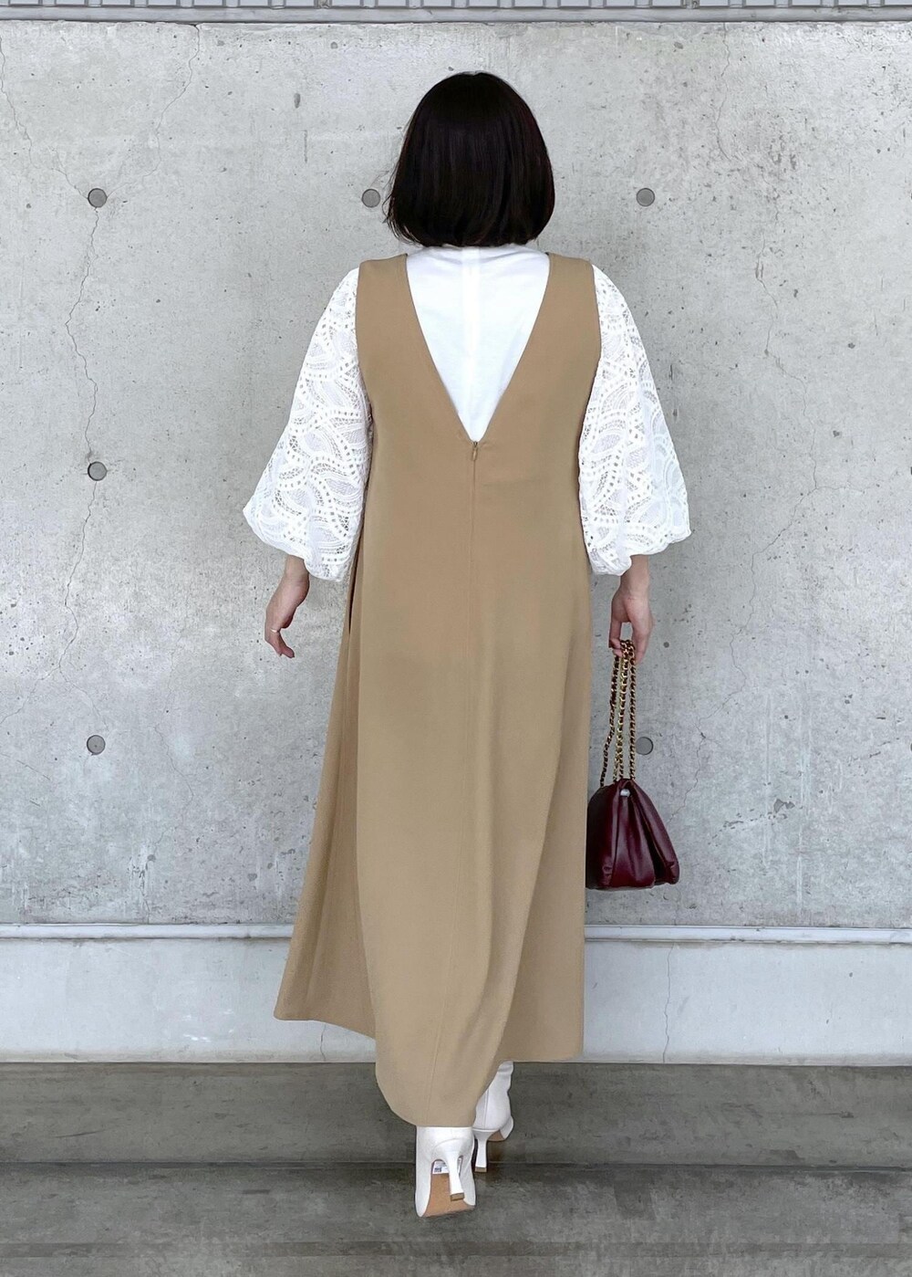 ホワイト系のブーツ、レッド系のハンドバッグ、ベージュ系のジャンパースカートを着用したレディースの秋コーディネートの6枚目の写真