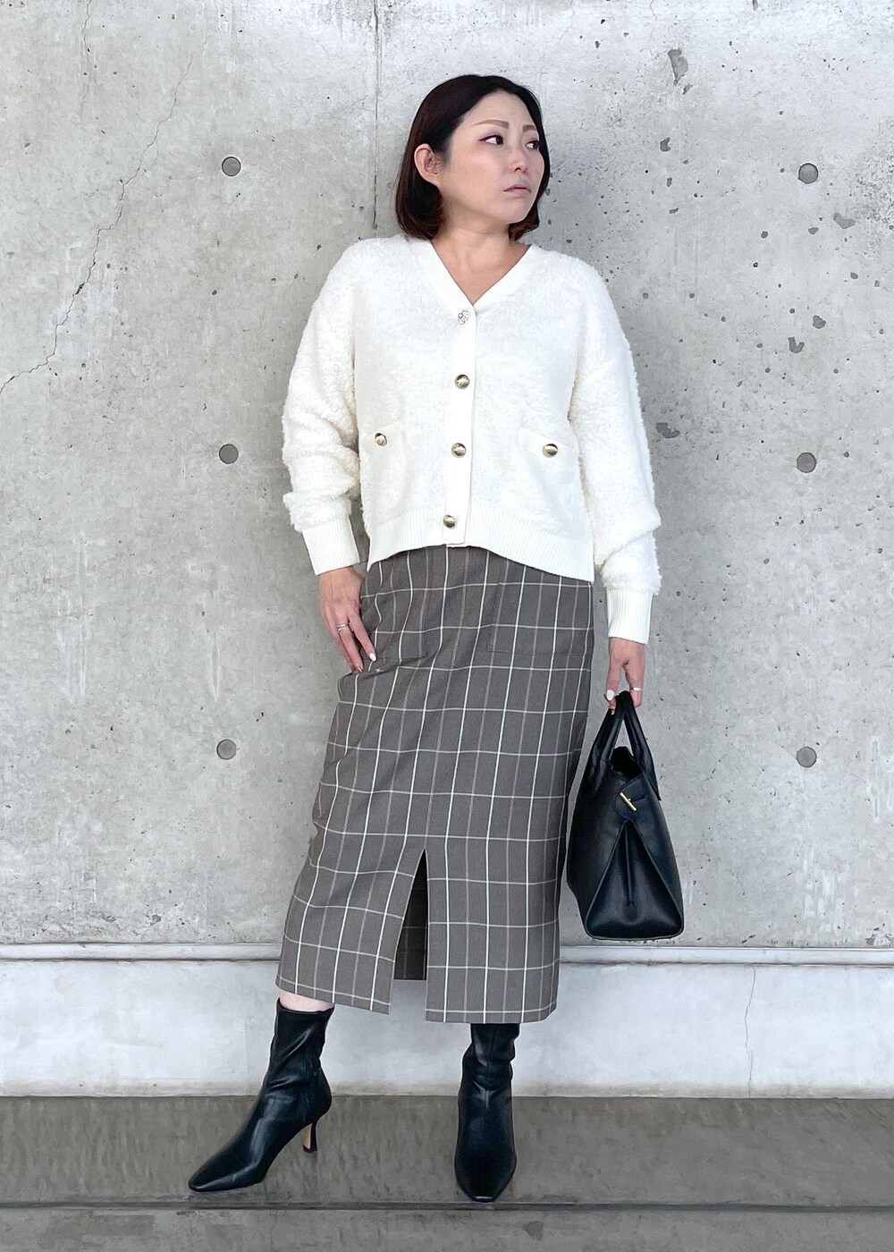 ブラック系のブーツ、ブラック系のトートバッグ、ブラウン系のスカートを着用したレディースの秋コーディネートの2枚目の写真