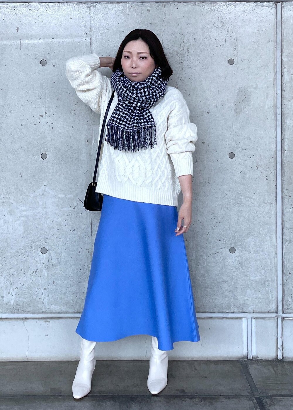 ブラック系のショルダーバッグ、ホワイト系のブーツ、ブルー系のスカートを着用したレディースの秋コーディネートの2枚目の写真
