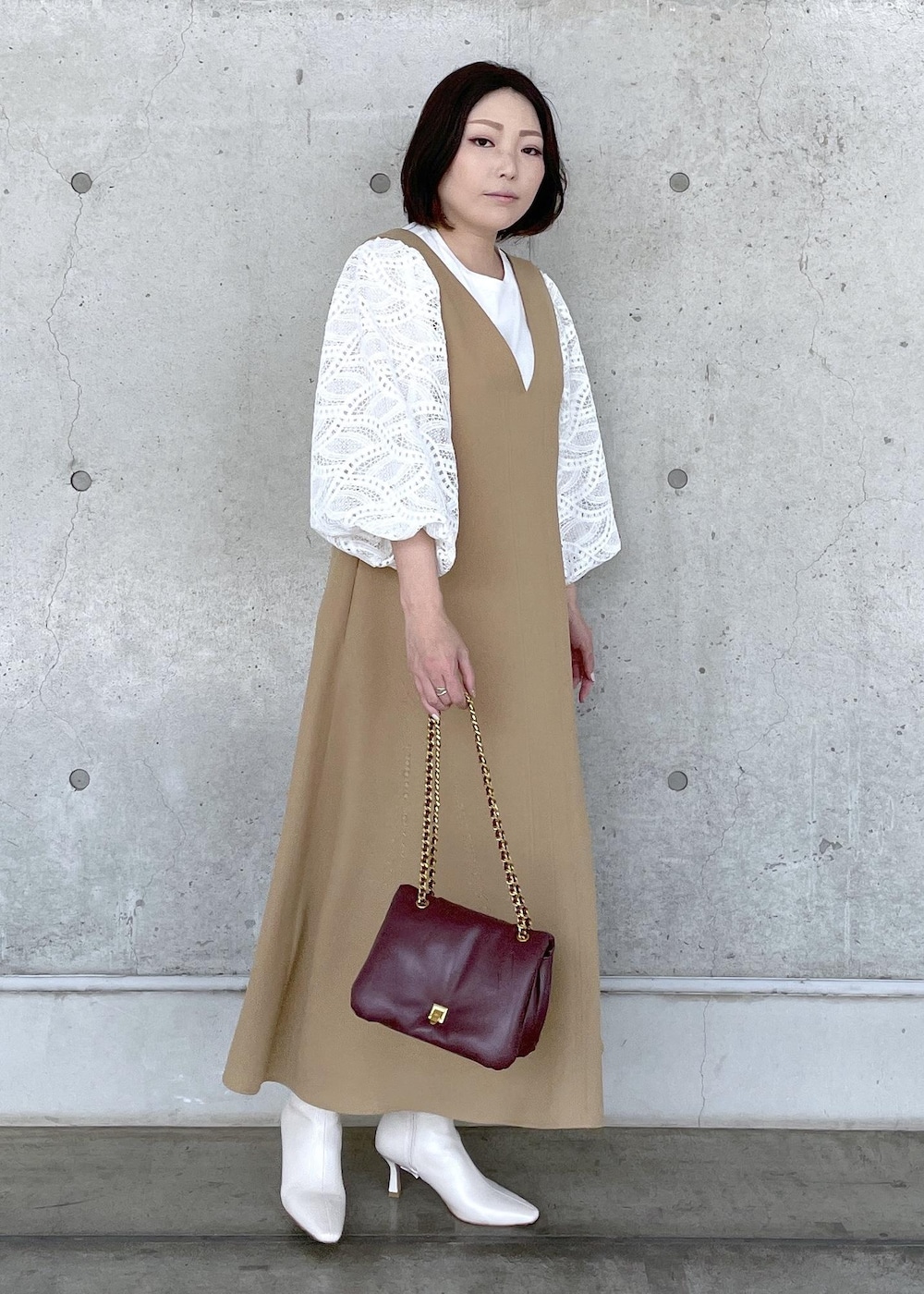 ホワイト系のブーツ、レッド系のハンドバッグ、ベージュ系のジャンパースカートを着用したレディースの秋コーディネートの4枚目の写真