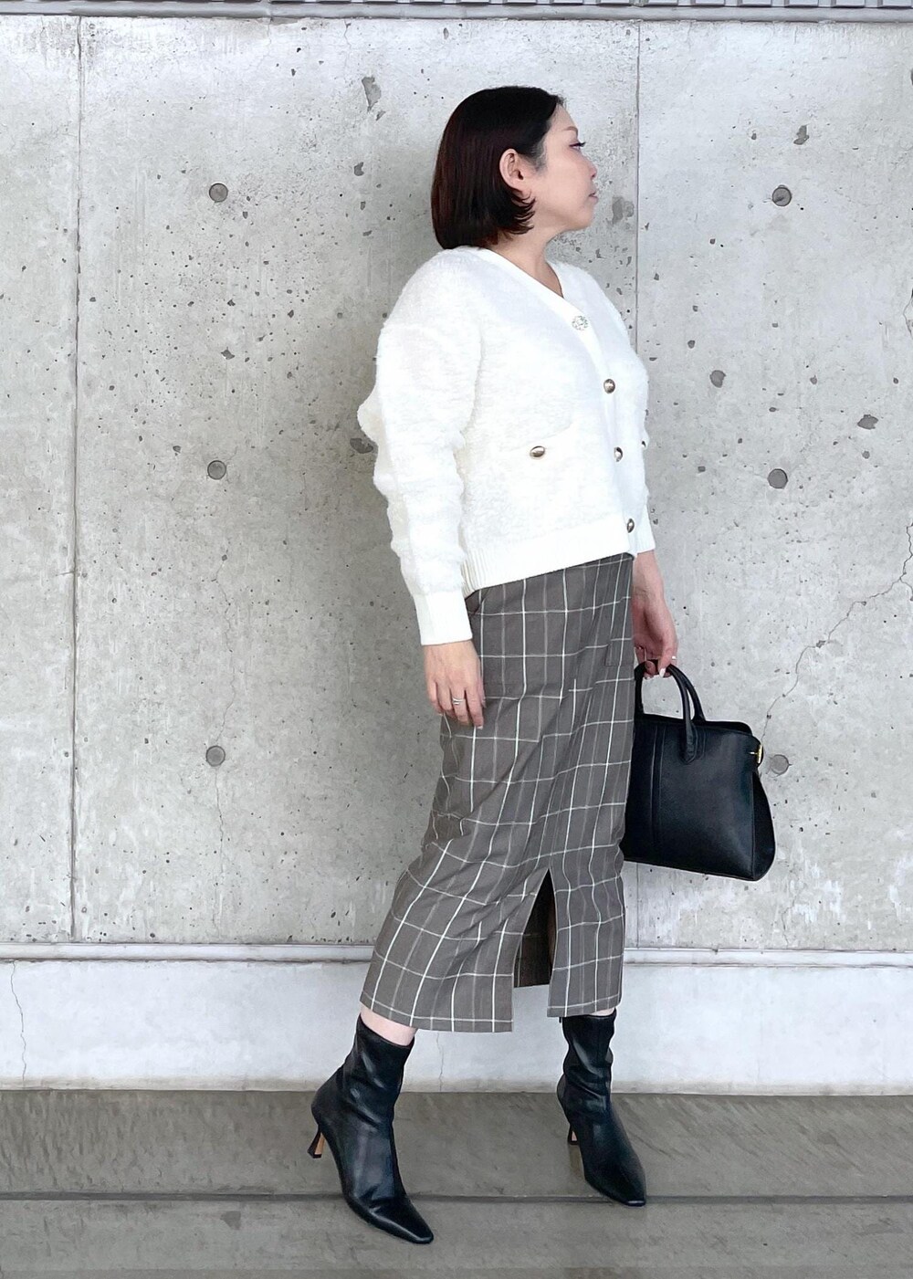 ブラック系のブーツ、ブラック系のトートバッグ、ブラウン系のスカートを着用したレディースの秋コーディネートの4枚目の写真