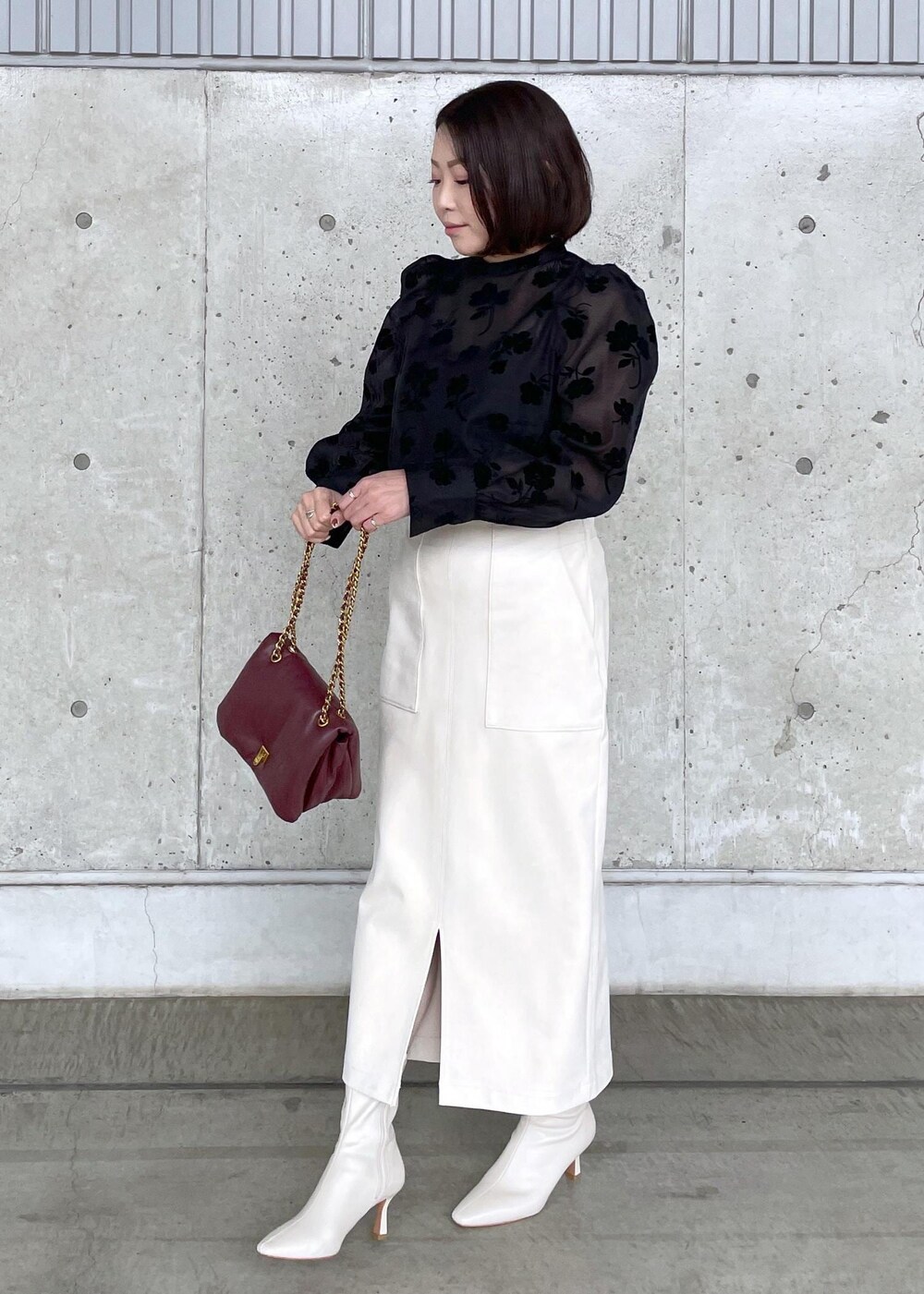 ホワイト系のブーツ、レッド系のハンドバッグ、ホワイト系のスカートを着用したレディースの秋コーディネートの4枚目の写真