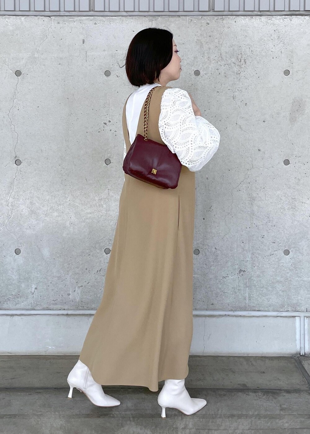 ホワイト系のブーツ、レッド系のハンドバッグ、ベージュ系のジャンパースカートを着用したレディースの秋コーディネートの5枚目の写真