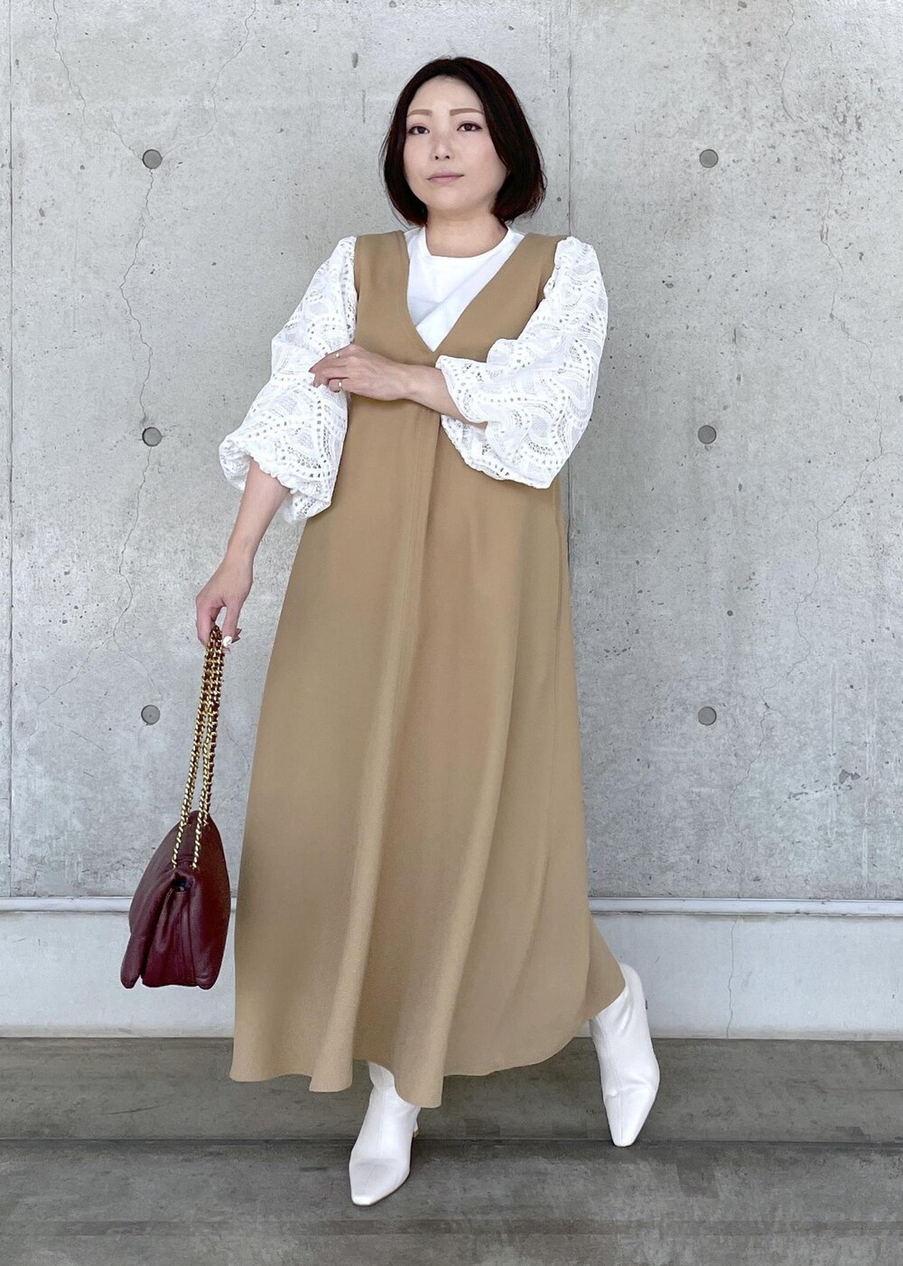 ホワイト系のブーツ、レッド系のハンドバッグ、ベージュ系のジャンパースカートを着用したレディースの秋コーディネートの2枚目の写真