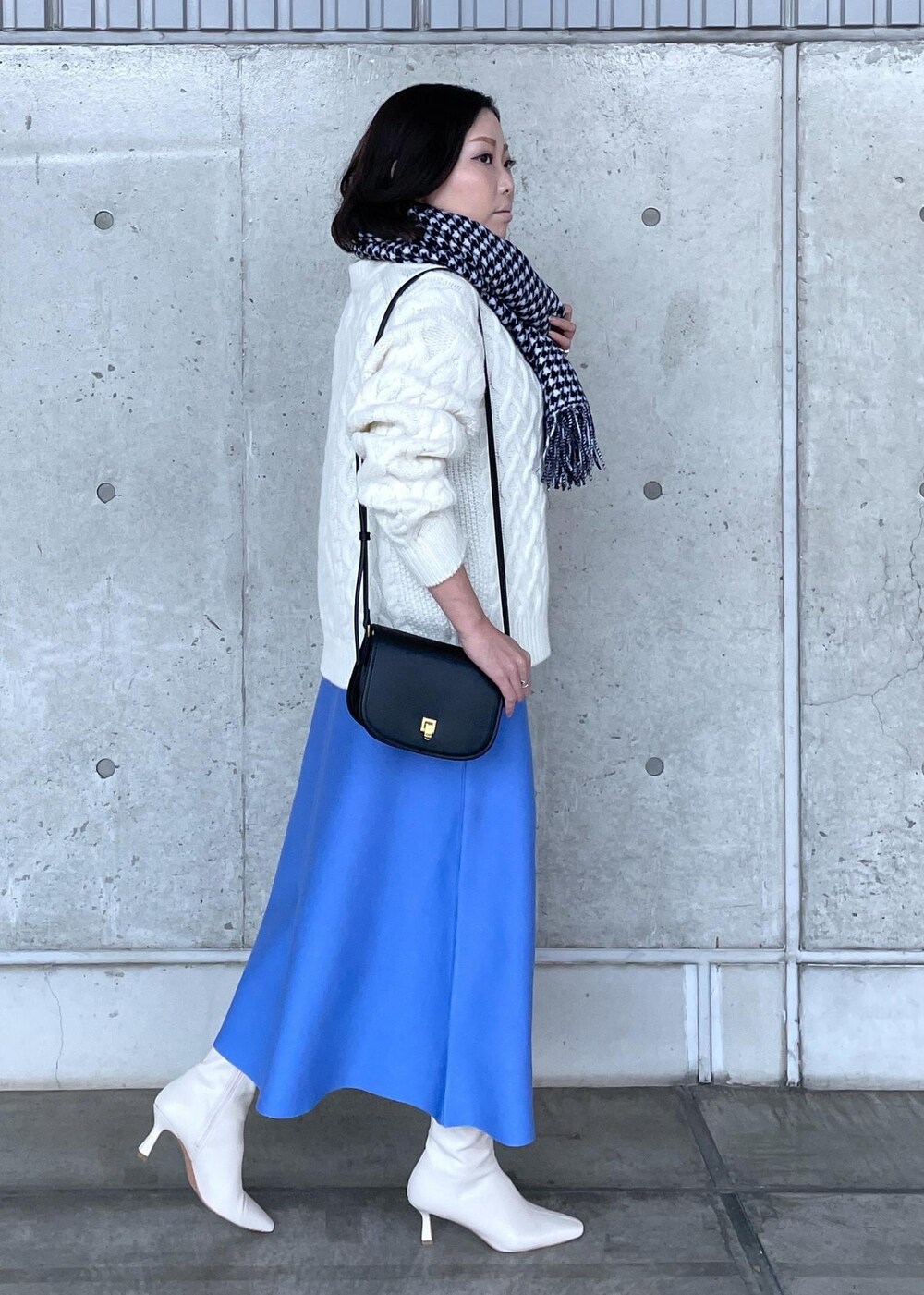 ブラック系のショルダーバッグ、ホワイト系のブーツ、ブルー系のスカートを着用したレディースの秋コーディネートの3枚目の写真